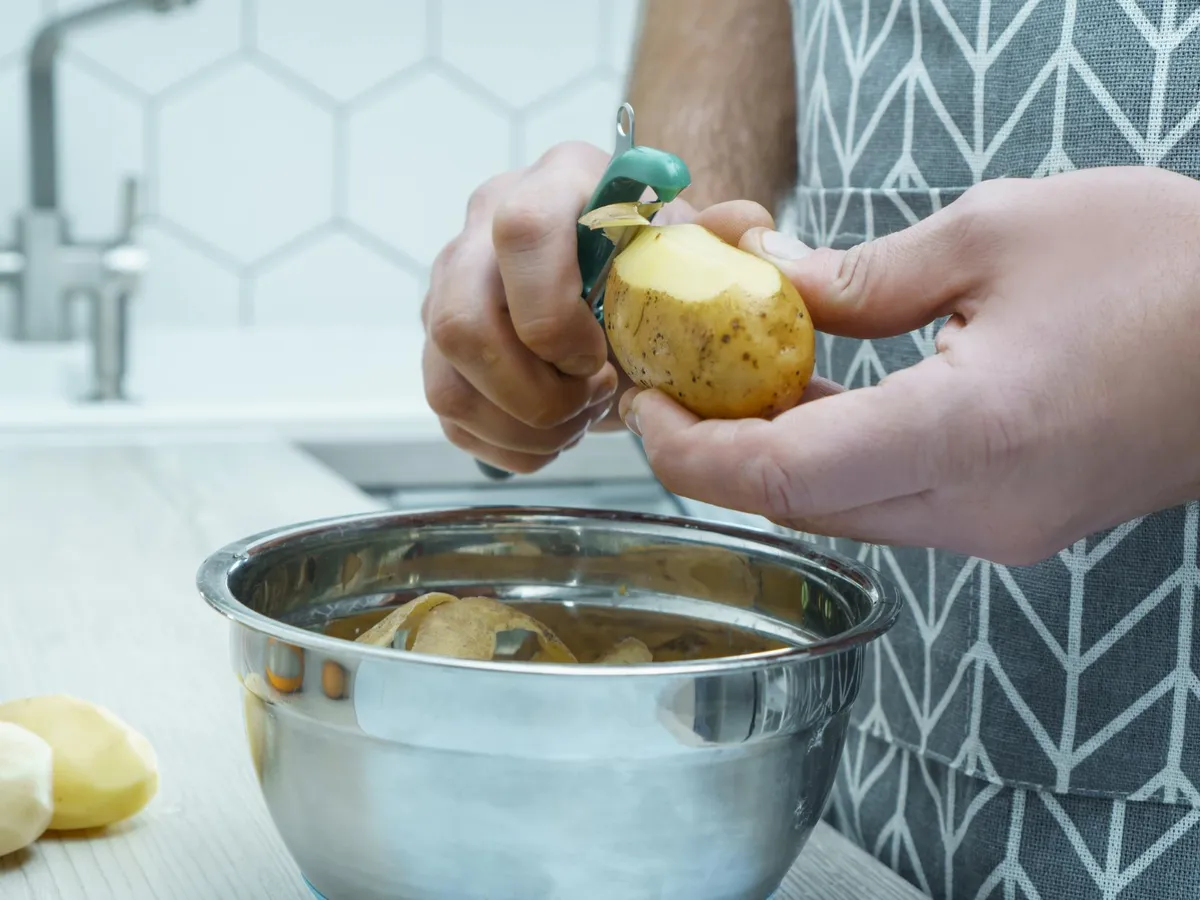 Persoană care curăță un cartof - Foto: Freepik (rol ilustrativ)
