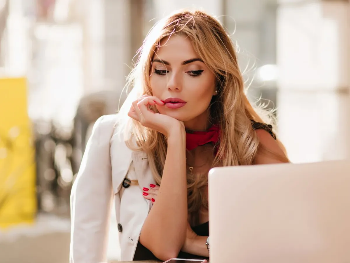 Tânără femeie de afaceri lucrând la computer, într-o cafenea - Foto: Magnific.com/lookstudio
