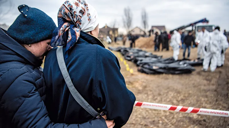 POVARA DOVEZILOR Femei privesc cum sunt exhumate cadavrele dintr-o groapă comună din Bucea, pentru ca autoritățile să le poată inspecta pentru a găsi dovezi ale unor posibile crime de război comise de forțele rusești