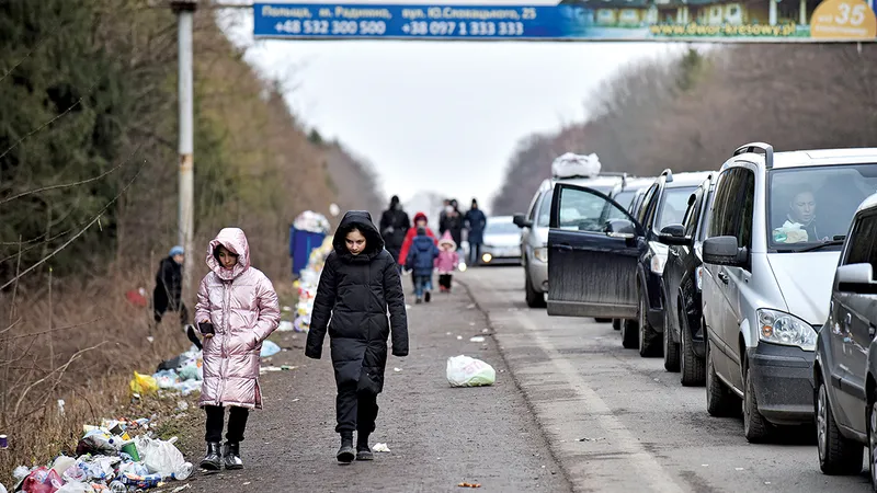 Copiii merg alături de un șir de mașini lung de 19 kilometri care așteaptă să treacă granița dintre Ucraina și Polonia
