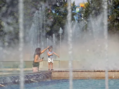 Femeie cu copil pe marginea unei fântâni, în Bucureşti - Foto: Profimedia Images