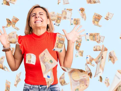 Femeie fericită cu bancnote de euro zburând în jurul ei - Foto: Magnific.com/krakenimages.com