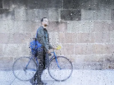 Bărbat pe bicicletă mergând pe stradă, prin ploaie - Foto: Freepik/CC0