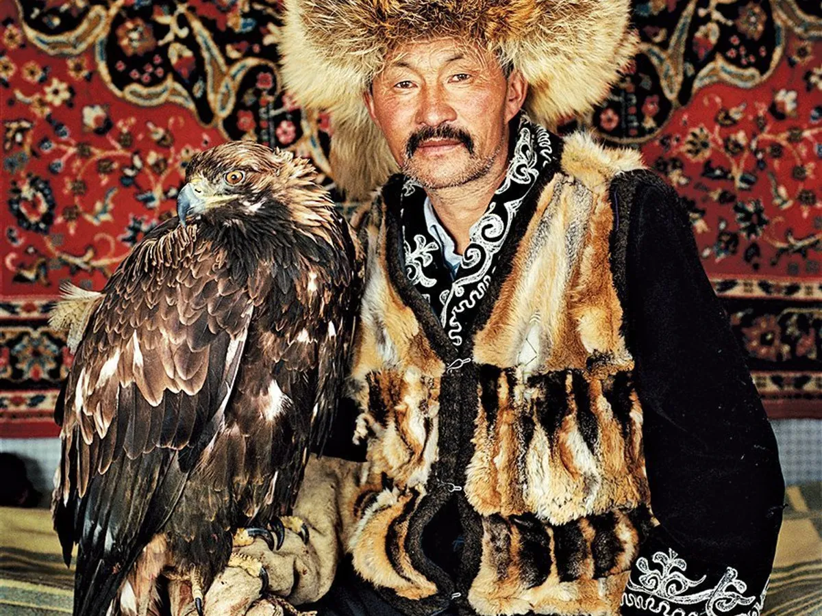 Dalaikhan, un vânător dintr-un sat de la poalele Munţilor Altai, purtând piei de vulpe de la prada prinsă de vulturul său