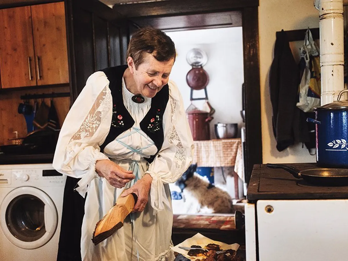 Româncă de origine germană punând lemne pe foc în satul Viscri