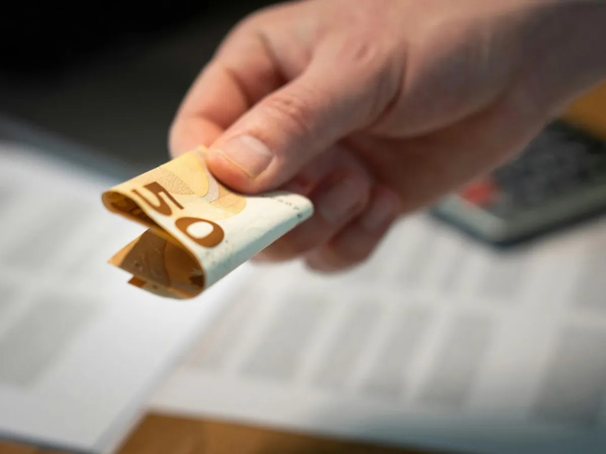 Bărbat ţinând în mână o bancnotă de 50 de euro - Foto: Pexels/Jakub Zerdzicki