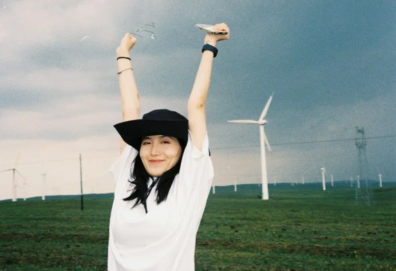 Femeie veselă cu fundal cu mori eoliene - Foto: Pexels/yating yang