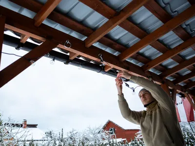 Bărbat care instalează luminițe pe casă - Foto: Freepik (Imagine cu rol ilustrativ)