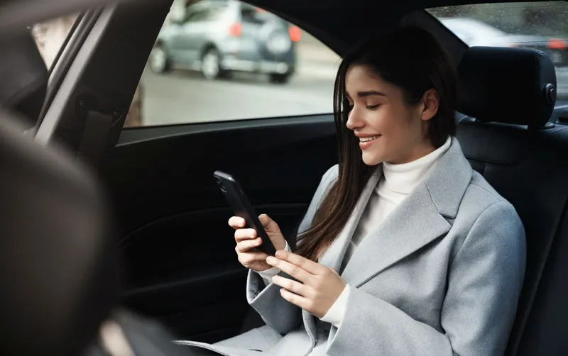 Femeie z&acirc;mbitoare făc&acirc;nd ride-hailing - Foto: magnific.com/lookstudio