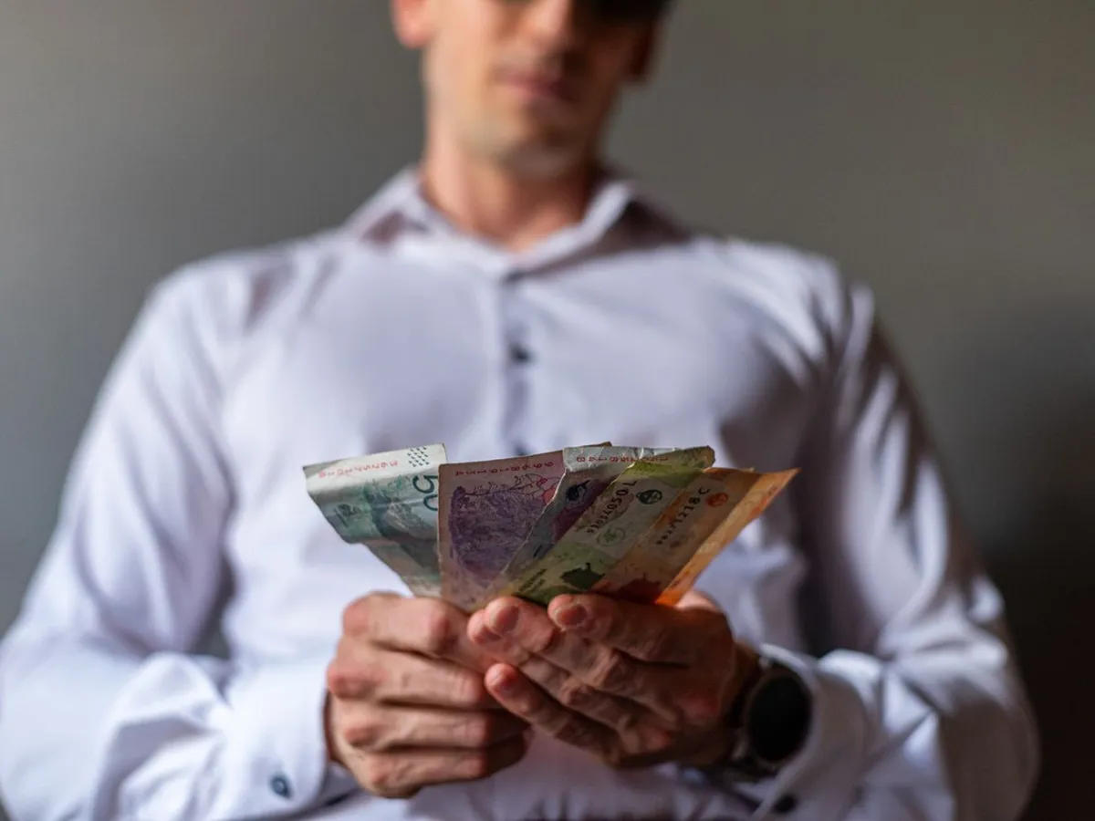 Bărbat care ține bancnote în mână - Foto: Pexels (Imagine cu rol ilustrativ)