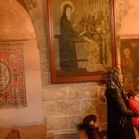 În această fotografie făcută pe 23 februarie 2020, o membră a comunității creștine asiriene stă cu copiii ei în timp ce participă la o masă de duminică, la biserica Mor Behnam Kirklar din Mardin, din sud-estul Turciei.. Foto Getty Images