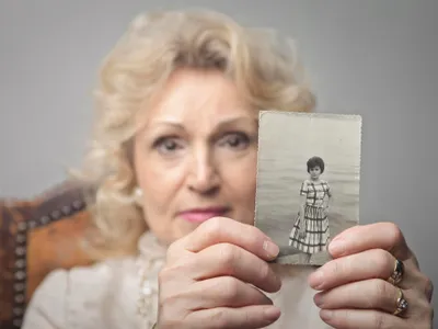 O bătrână care ține în mână o fotografi veche - Foto: Freepik