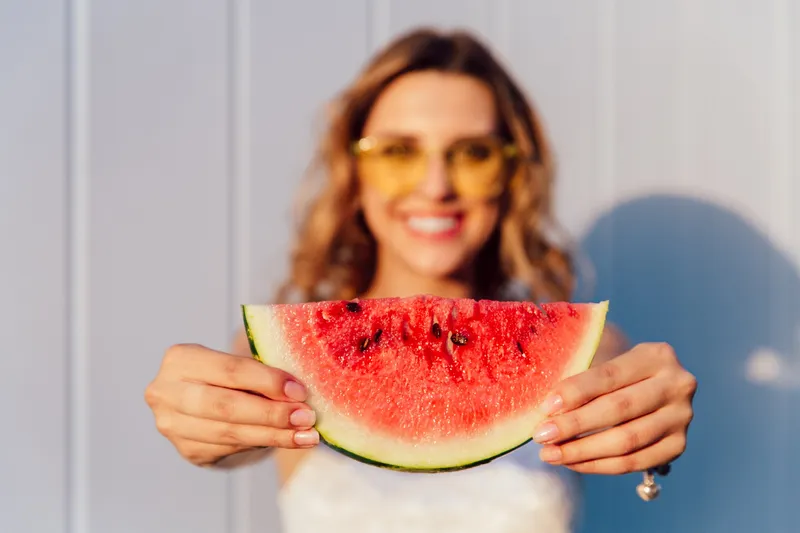 Fată veselă și fermecătoare care ține o bucată de pepene verde - Foto: Magnific.com (Imagine cu rol ilustrativ)