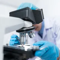 Cercetător analizând o probă la microscop - Foto: Pexels/Chokniti Khongchum