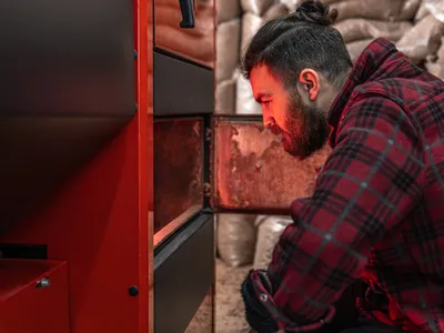 Un bărbat într-o cameră cu o centrală pe lemne - Foto: Magnific.com (Imagine cu rol ilustrativ)