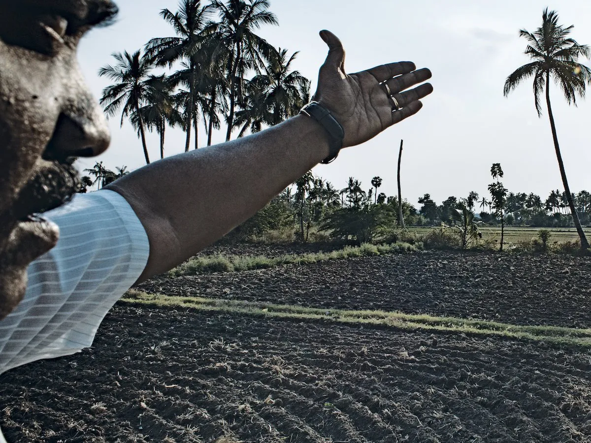 Karthik, un activist din cadrul Asociaţiei Fermierilor din India de Sud, gesticulează către pământurile sale acum sterpe