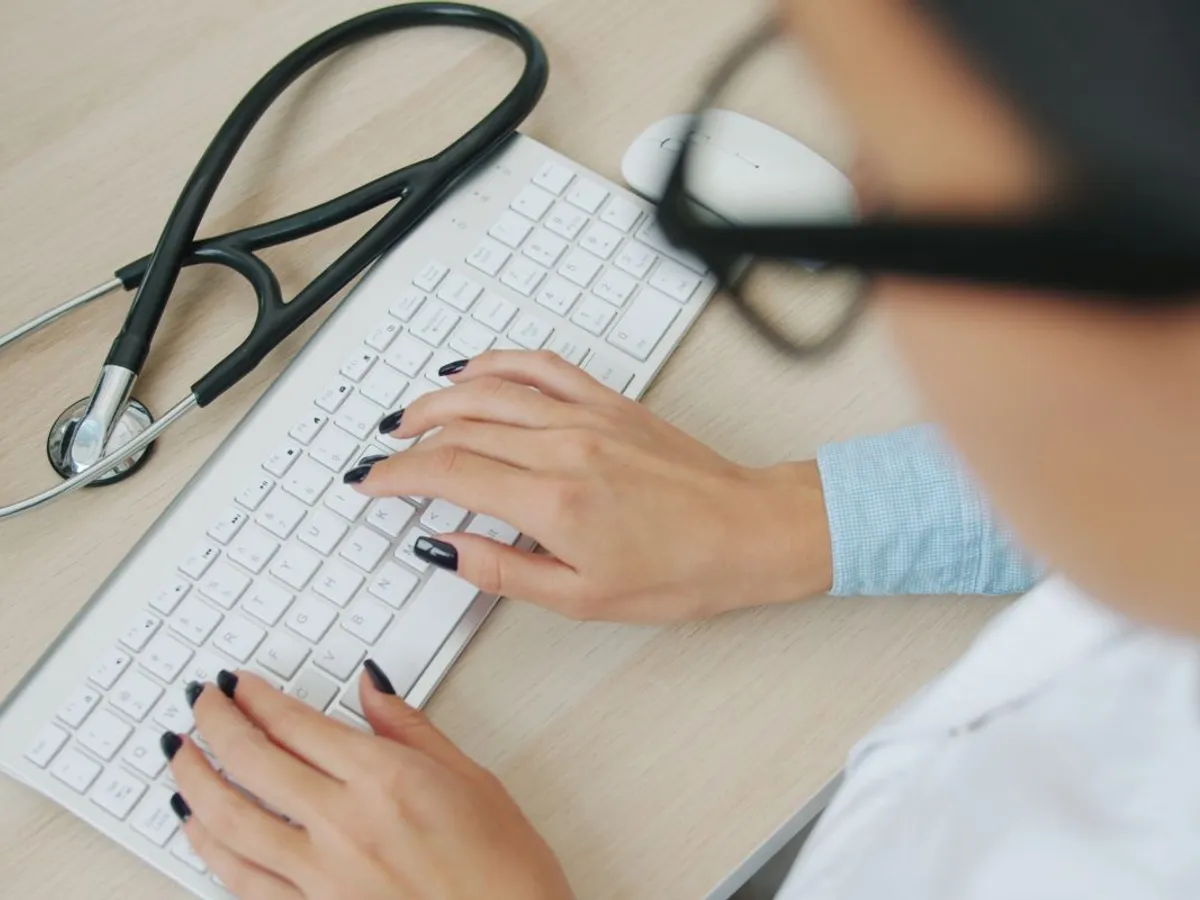 Doctoriţă documentându-se pe laptop - Pexels/Vitaly Gariev