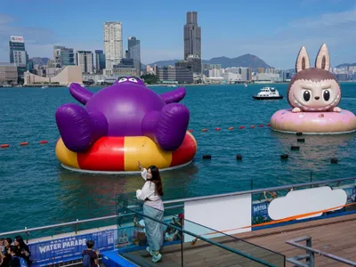 O femeie priveşte o sculptură gonflabilă plutitoare reprezentând păpuşile Grimes și Labubu - Foto: Profimedia Images