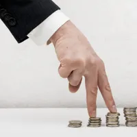 Mână cu degete pe monede, simbolizând inflaţie în creştere - Foto: Magnific.com/magnific