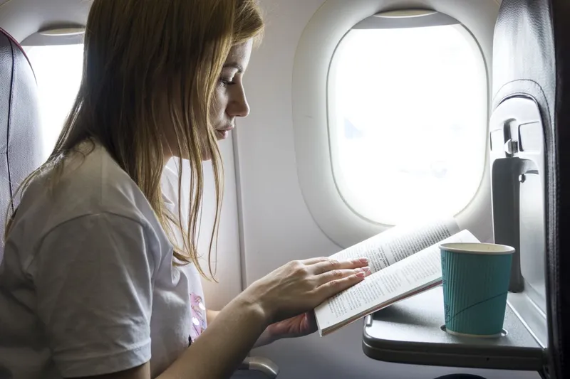 Femeie citind o carte, &icirc;n avion - Foto: Magnific.com/freepik