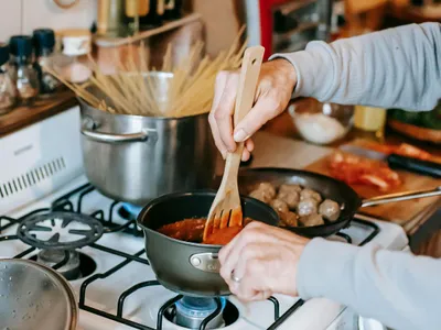 Femeie gătind pe aragaz calsic, folosind gaze naturalle - Foto: Pexels/Gary Barnes