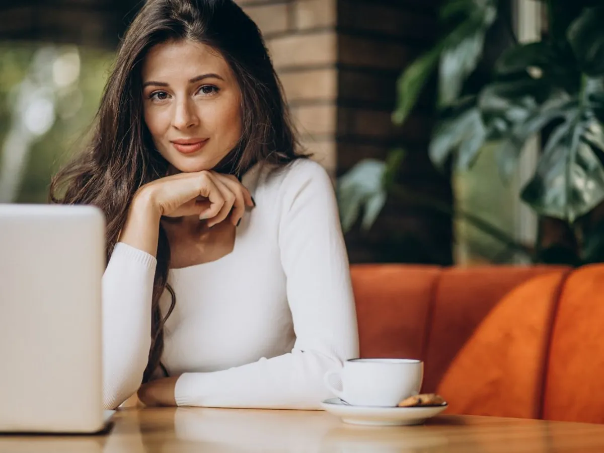 Tânără femeie de afaceri lucrând la computer, într-o cafenea - Foto: Magnific.com/senivpetro