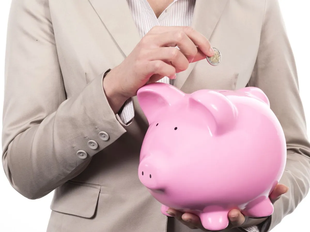 Femeie punând bani la puşculiţă - Foto: Freepik/kues1