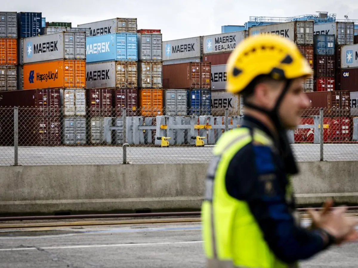 Un vameș stă în fața unor containere de transport stivuite în Portul Rotterdam - Foto: Profimedia Images