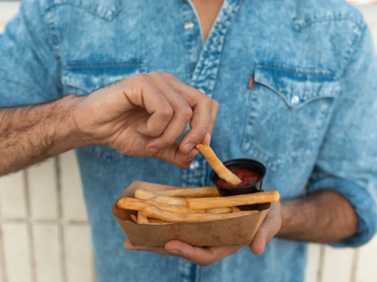 Persoană care manancă cartofi prăjiți - Foto: Pexels (Imagine cu rol ilustrativ)