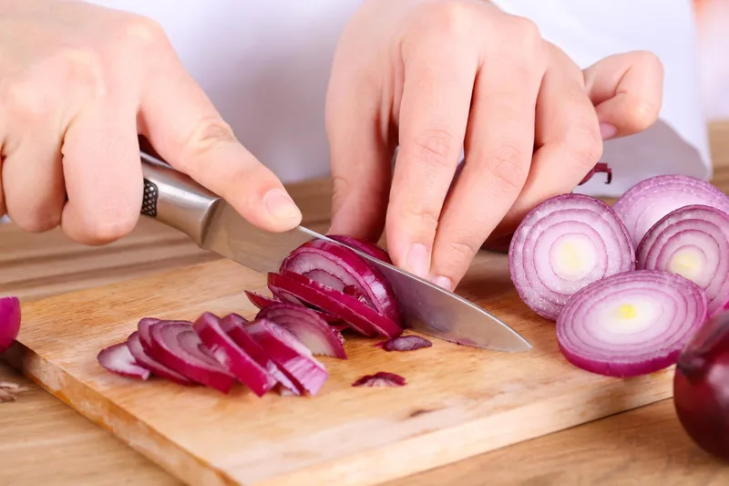 Persoană care taie o ceapă - Foto: Freepik (Imagine cu rol ilustrativ)