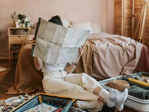 Femeie relaxată cercetând o hartă, în locuinţa ei - Foto: Pexels/Vlada Karpovich
