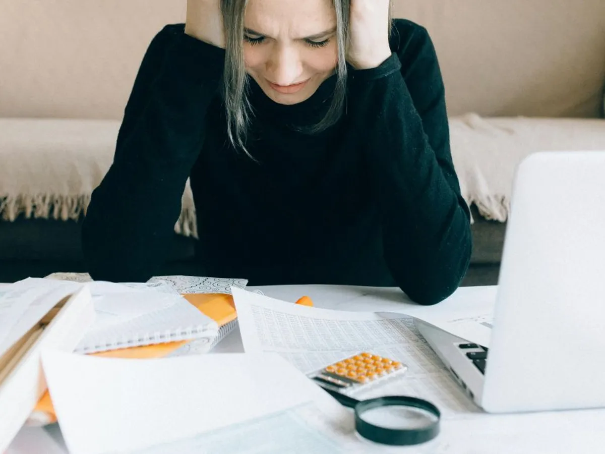 Femeie luându-se cu mâinile de cap, atunci când face calcule - Foto: Pexels/Nataliya Vaitkevich
