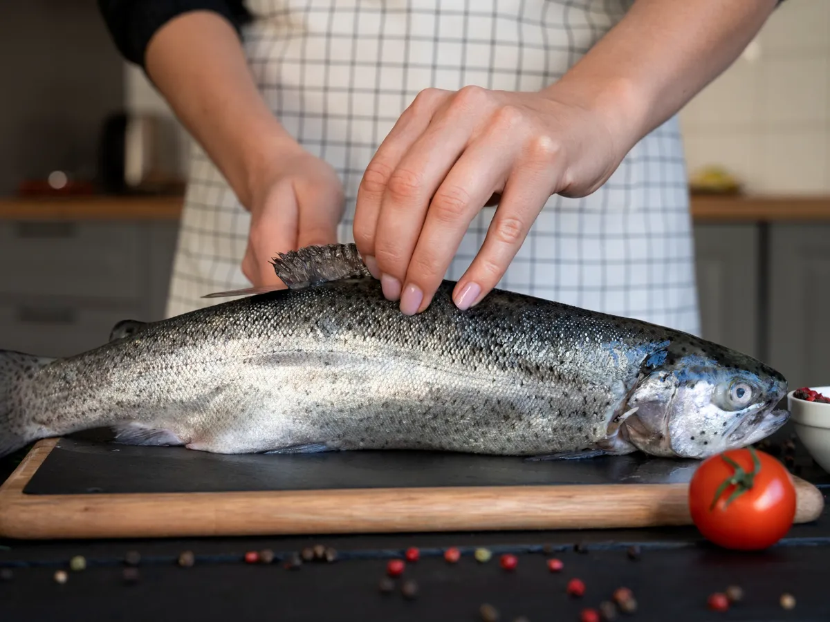 Persoană care gătește un pește - Foto: Freepik (Imagine cu rol ilustrativ)