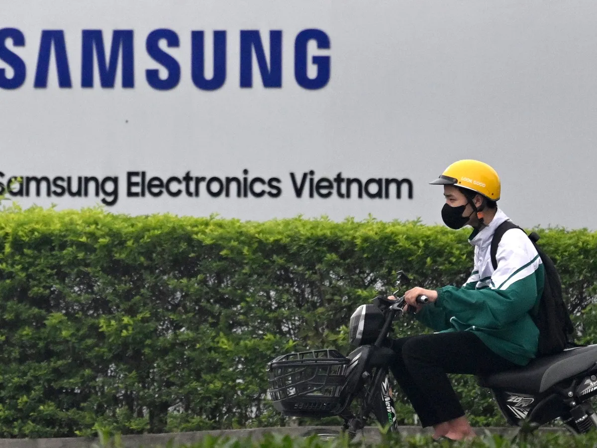 Un bărbat conduce o motocicletă electrică, pe lângă sigla Samsung Electronics. Coreenii, în căutare de salarii mici, au construit ani de zile aproape jumătate din telefoanele lor aici - Foto: Profimedia Images