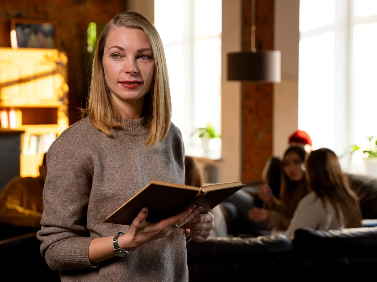 Femeie zâmbitoare cu plan mediu, ținând o carte - Foto: Freepik (Imagine cu rol ilustrativ)