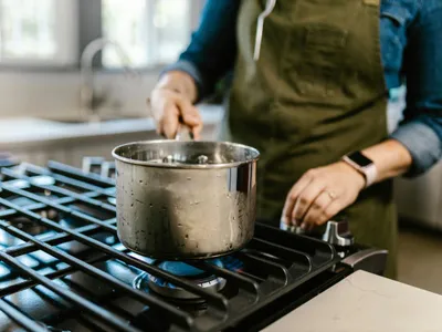 Femeie pregătind mâncarea, pe aragaz, în oală - Foto: Pexels/RDNE Stock project