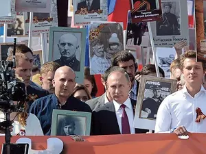 VLADIMIR PUTIN, cu fotografia tatălui său, care a luptat în Armata Roșie în timpul celui de-Al Doilea Război Mondial. Imaginea a fost răspândită de organul de propagandă al Rusiei, Sputnik.