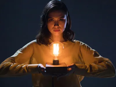 Femeie ţinând în mână un stand cu un bec - Foto: Pexels/Ron Lach