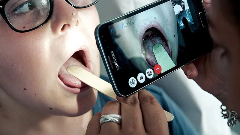 Un doctor examinează gâtul unui copil dintr-un sat îndepărtat din Franța, prin video de pe smartphone