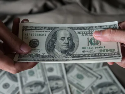 Persoană care ține în mână dolari americani - Foto: Freepik (rol ilustrativ)
