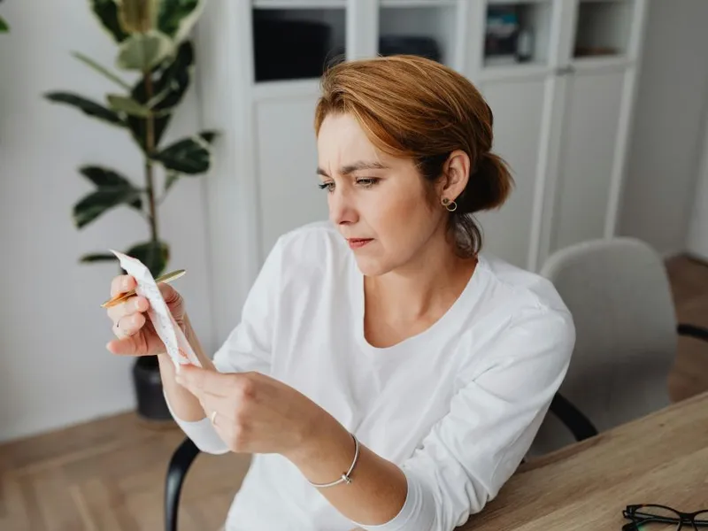 Femeie la birou, uitându-se la fluturaşul de salariu - Foto: Pexels/Kaboompics.com
