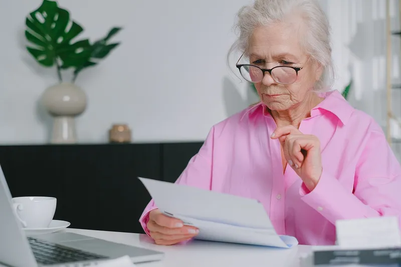 Pensionară se uită la acte