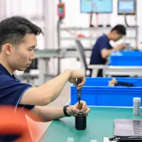 Doi tehniicieni chinezi asamblează componente ale unui robot umanoid, pe linia-pilot de asamblare - Foto: Profimedia Images