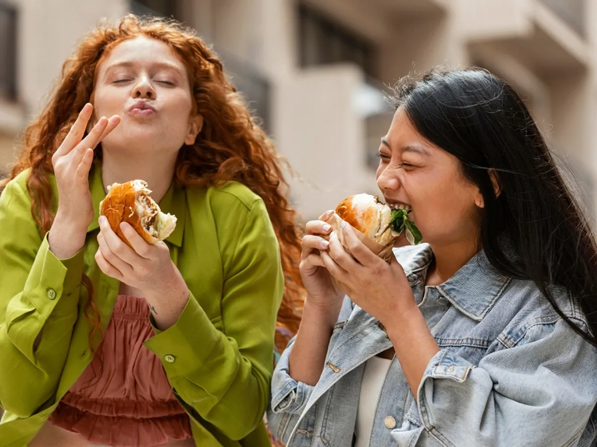 Două femei mănâncă hamburgeri - Foto: Freepik (rol ilustrativ)