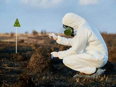 Cercetător, pe un câmp ars, luând probe biologice - Foto: Magnific.com/ArtPhoto_studio