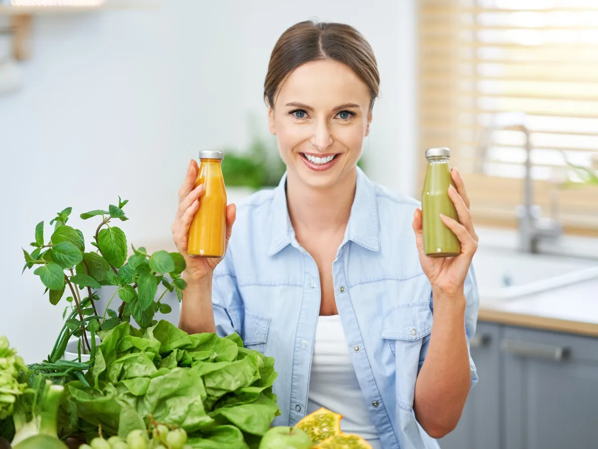 Femeie care ține în mână două sticle de suc natural - Foto: Freepik (imagine cu rol ilustrativ)