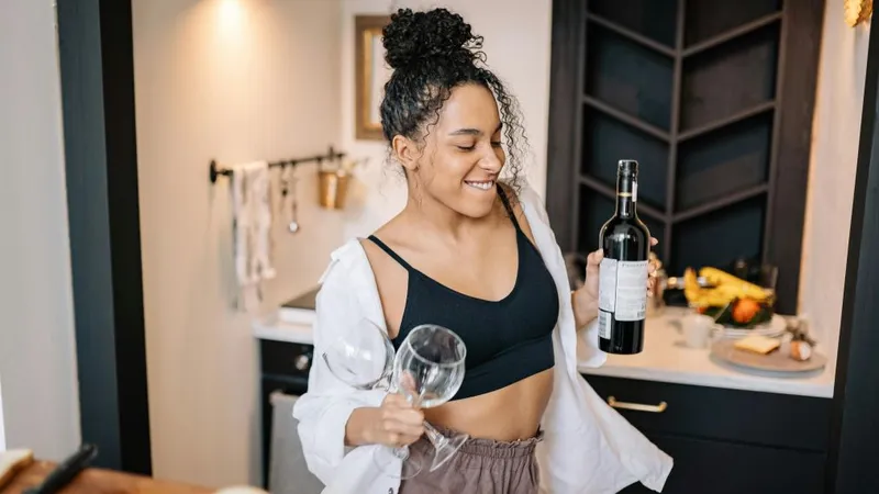 Femeie dansând, în timp ce ţine în mână o sticlă de vin - Foto: Pexels/Yan Krukau