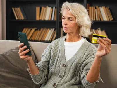 Pensionară verifică un card - Foto: Freepik