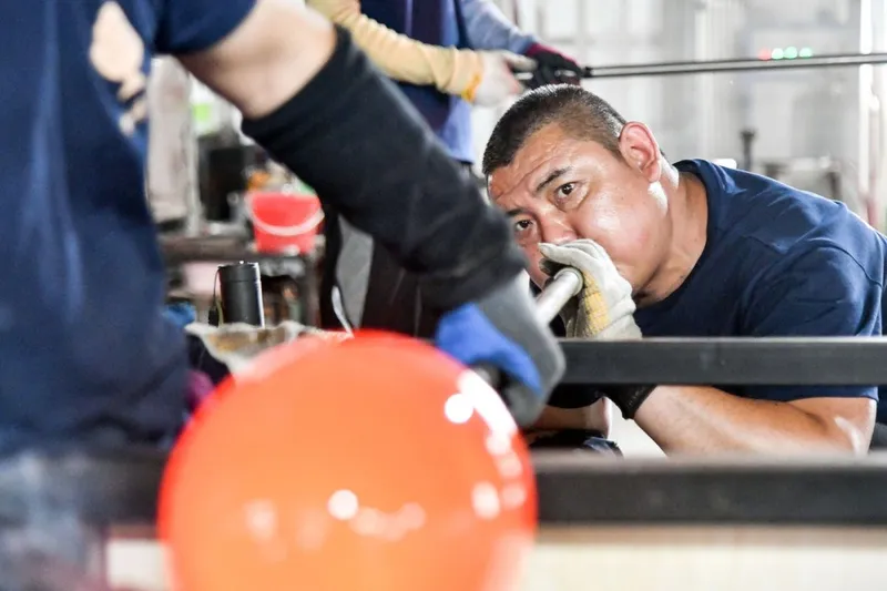Un meșter chinez realizează o operă de artă cu glazură colorată, &icirc;ntr-un atelier - Foto: Profimedia Images
