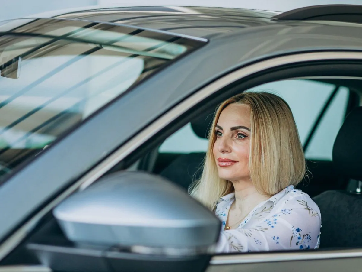 Femeie frumoasă râzând, de la volanul unei maşini - Foto: Magnific.com/senivpetro